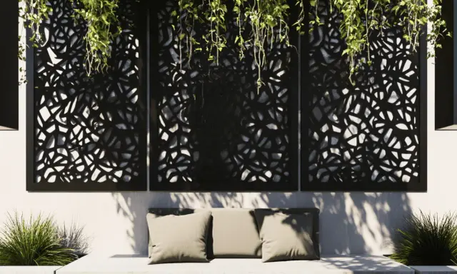 Comment cacher un vilain mur extérieur : des panneaux ajourés noirs avec des plantes retombantes créent une ambiance cosy sur un banc.