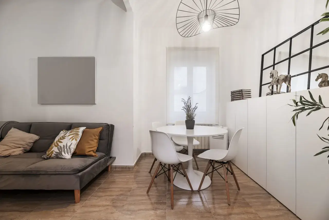 Idée pour aménager salon salle à manger 20m2 : canapé gris, table ronde blanche avec chaises, et rangements muraux.