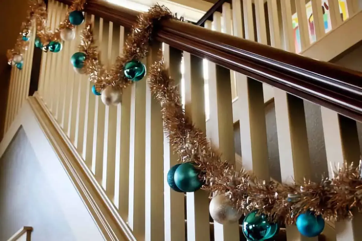 Guirlande dorée et boules de Noël bleues et blanches pour décorer une rampe d'escalier pour Noël.