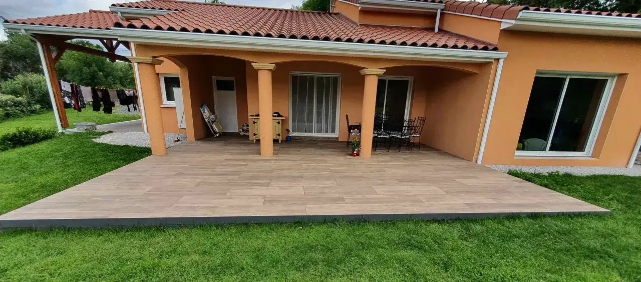Une terrasse moderne avec un nouveau carrelage extérieur effet bois, prolongeant l'espace de vie de la maison.