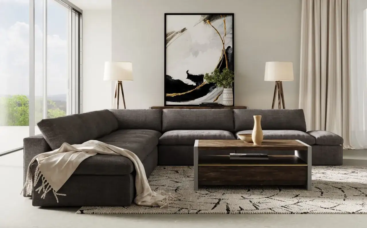 Un salon moderne avec un grand canapé d'angle gris foncé, une table basse en bois et métal, et une œuvre d'art abstraite.
