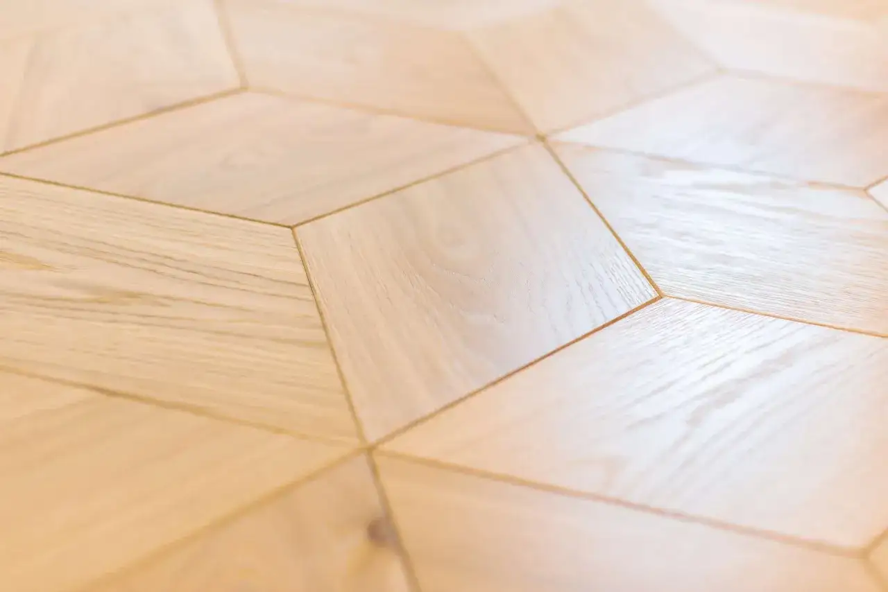 Calepinage parquet en bois clair, motif géométrique en losanges. L'effet visuel est moderne et lumineux.