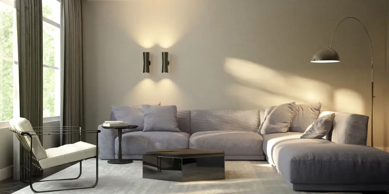 Salon moderne avec canap&eacute; gris, fauteuil blanc, table basse miroir et &eacute;clairage mural, cr&eacute;ant une ambiance chaleureuse sans plafonnier.