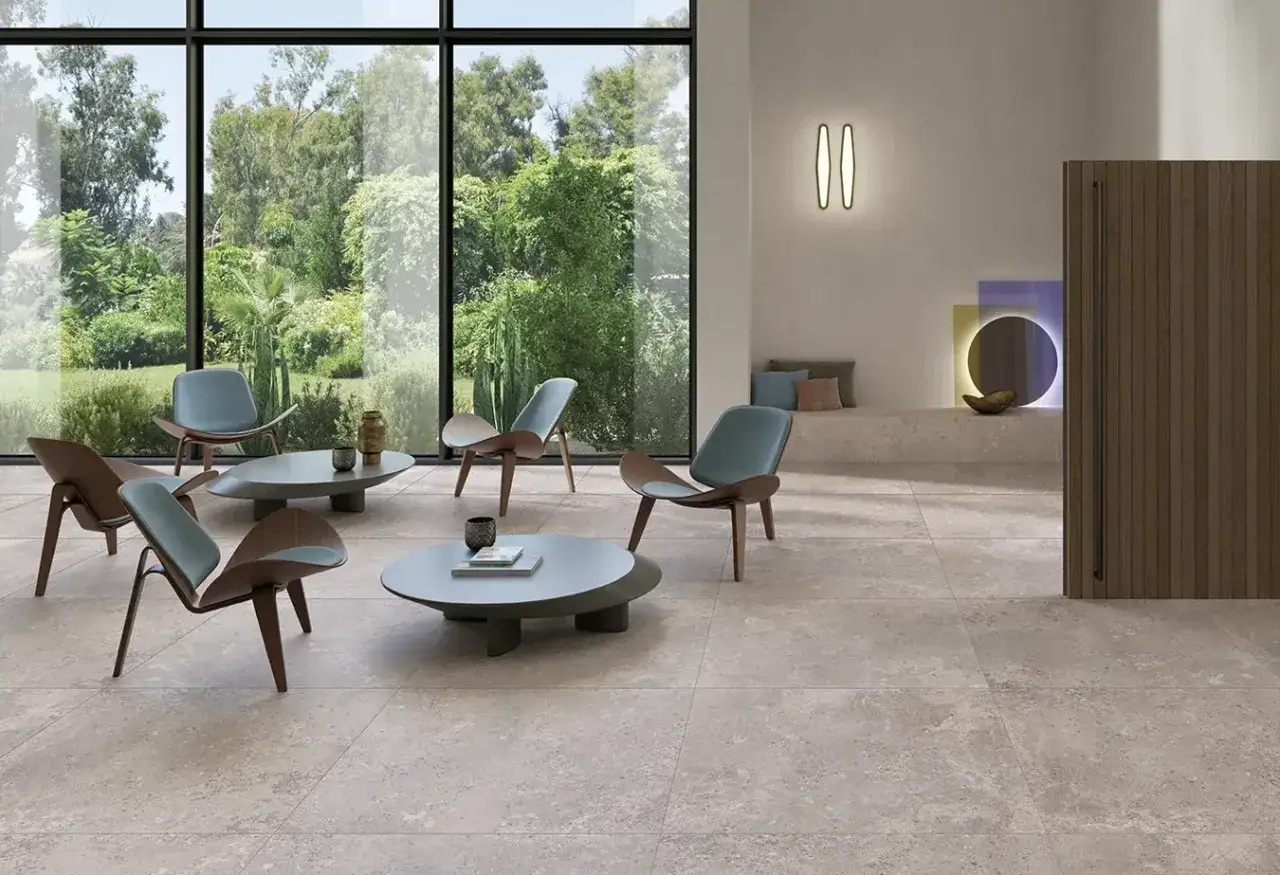 Un salon moderne avec des chaises design et des tables basses, le tout sur un carrelage pièce de vie tendance. La lumière naturelle inonde l'espace grâce aux grandes baies vitrées.