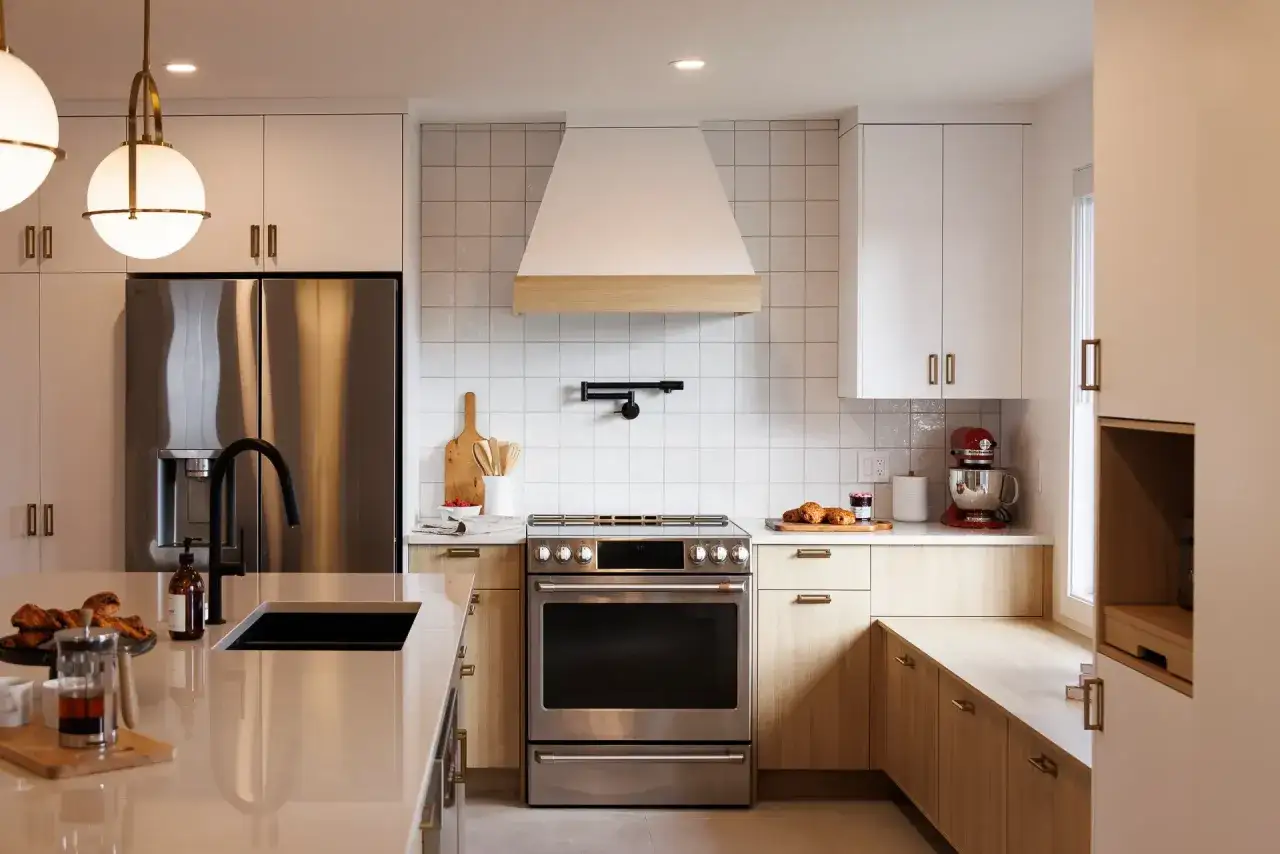 Cuisine moderne avec îlot, réfrigérateur en inox, hotte blanche et bois. Idées pour comment rénover une cuisine.