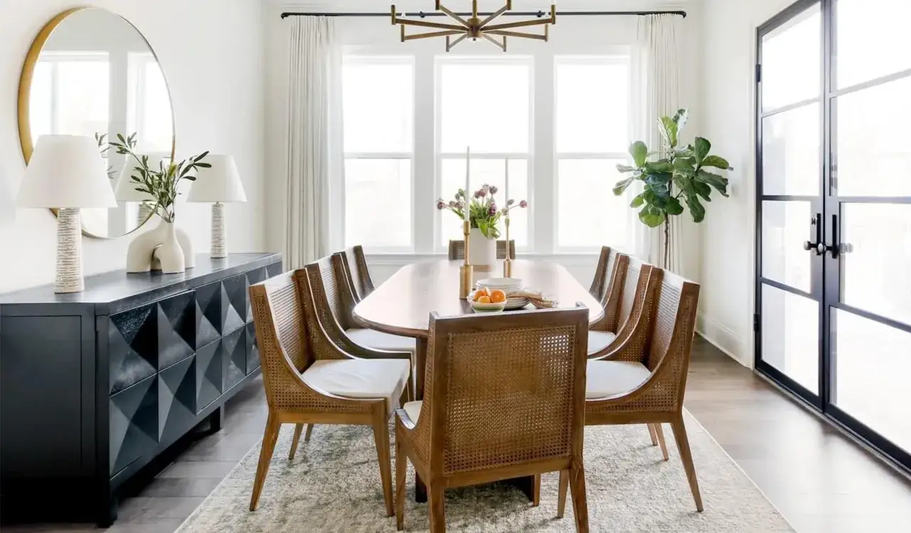 Salle &agrave; manger moderne avec table ovale et chaises en rotin. La largeur de la table &agrave; manger permet d'accueillir confortablement huit personnes.