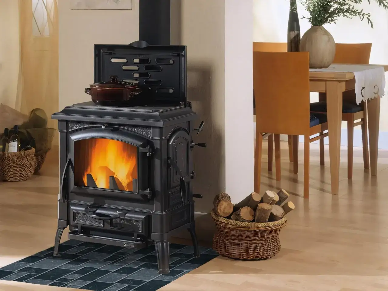 Un poêle à bois noir avec une cocotte sur le dessus, posé sur un carrelage sombre. Quel parement derrière poele à bois ? Une ambiance chaleureuse.