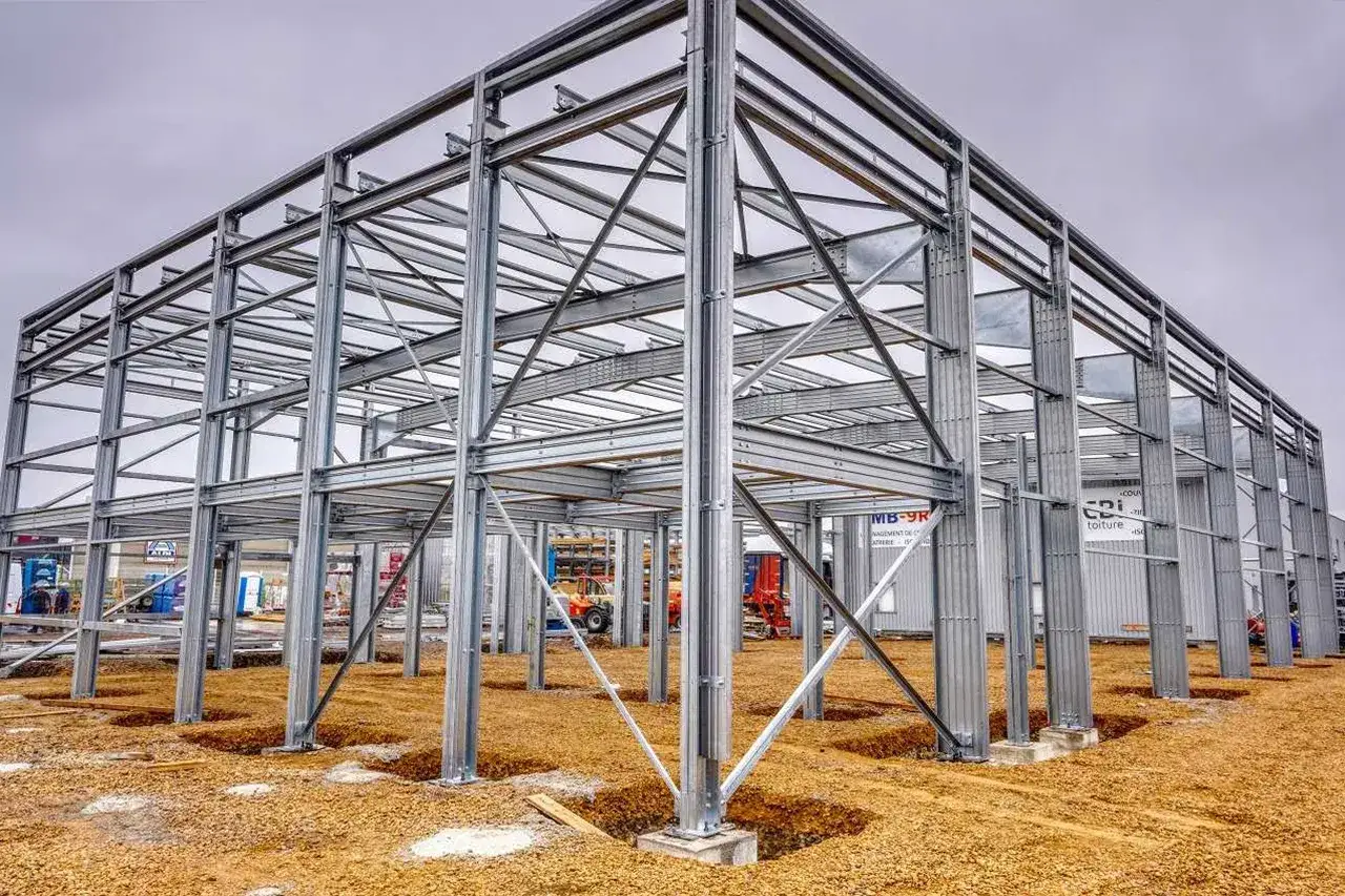 Imposante structure métallique en cours de construction, avec des poutres et des colonnes d'acier formant les fondations d'un nouveau bâtiment.