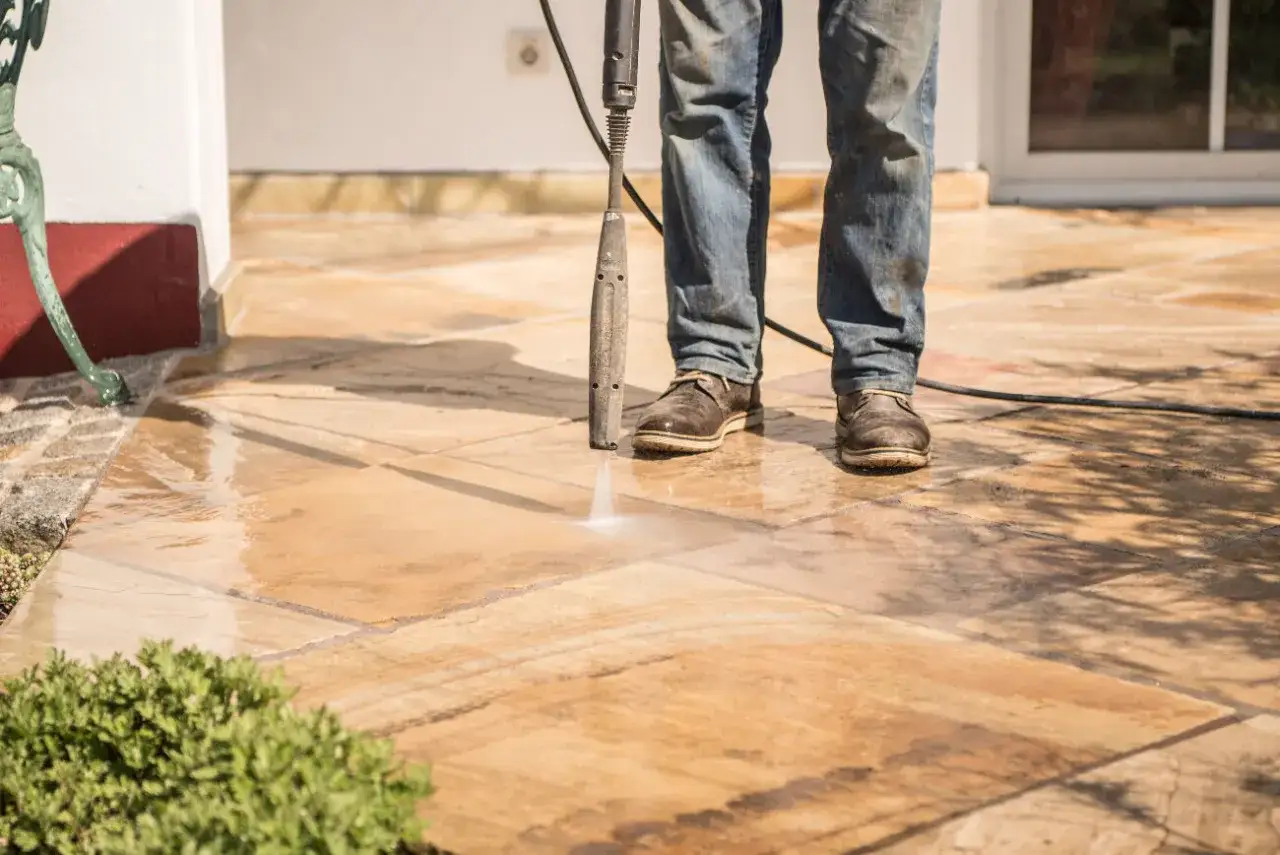 Nettoyer carrelage extérieur antidérapant avec un nettoyeur haute pression. L'eau nettoie les dalles en pierre.