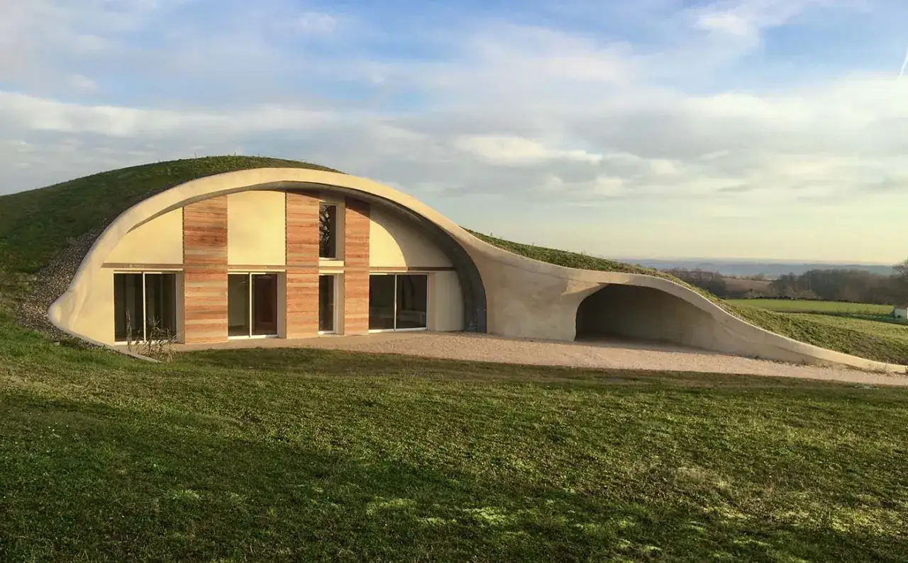 Maison écologique en terre, une construction ptz unique, intégrée dans le paysage verdoyant.