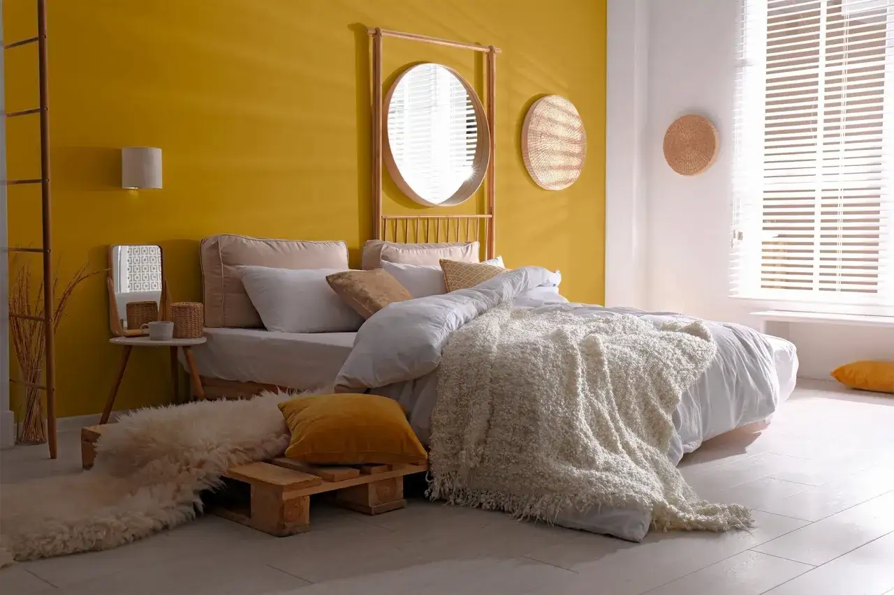 Un jaune moutarde éclatant pour une chambre chaleureuse. Un lit douillet, des coussins moelleux et une décoration bohème.