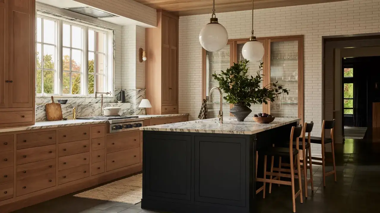 Cuisine moderne avec îlot noir, armoires en bois clair et marbre. La couleur cuisine industrielle est subtilement évoquée par les matériaux bruts et le contraste des teintes.