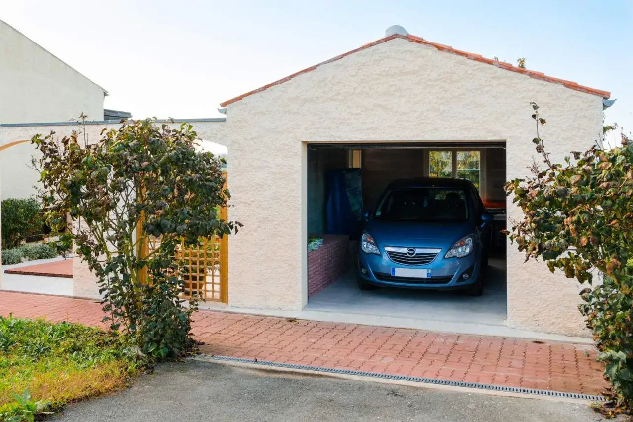 Un garage moderne avec une voiture bleue garée à l'intérieur. Le prix de construction de ce garage est raisonnable pour un tel espace.