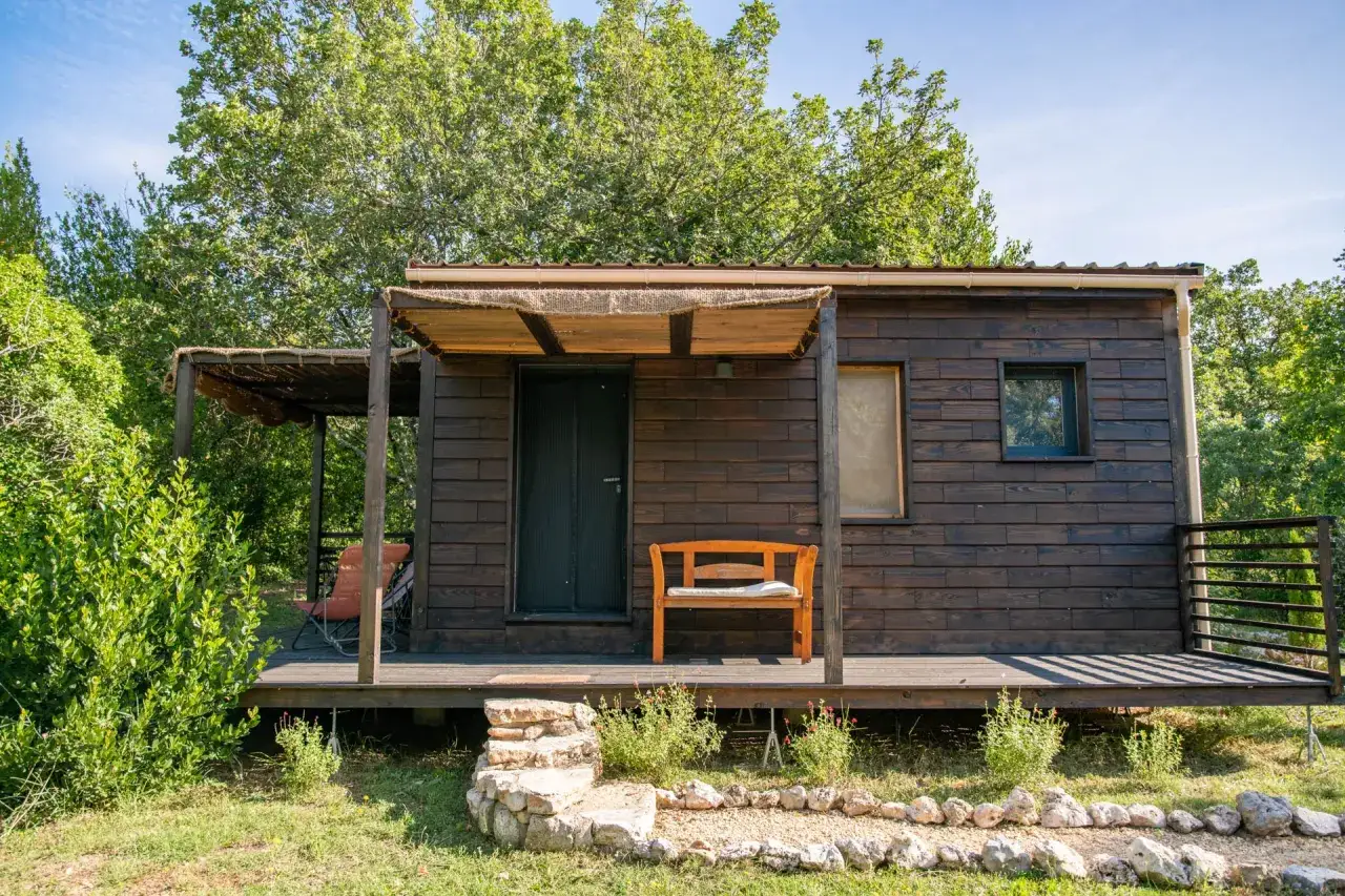 Charmante maison passive ossature bois, avec terrasse en bois et banc invitant à la détente. Entourée de verdure.