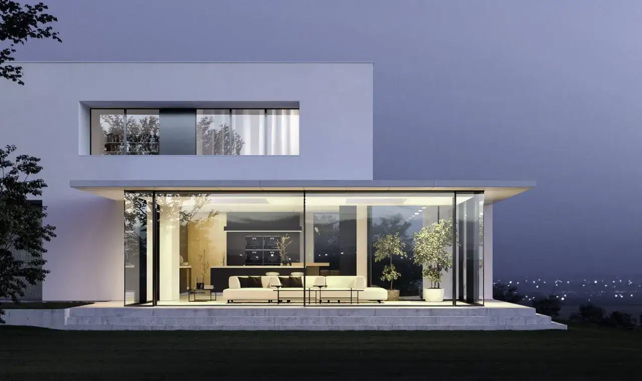 Une maison design moderne avec de grandes baies vitrées illuminées, révélant un salon et une cuisine épurés.