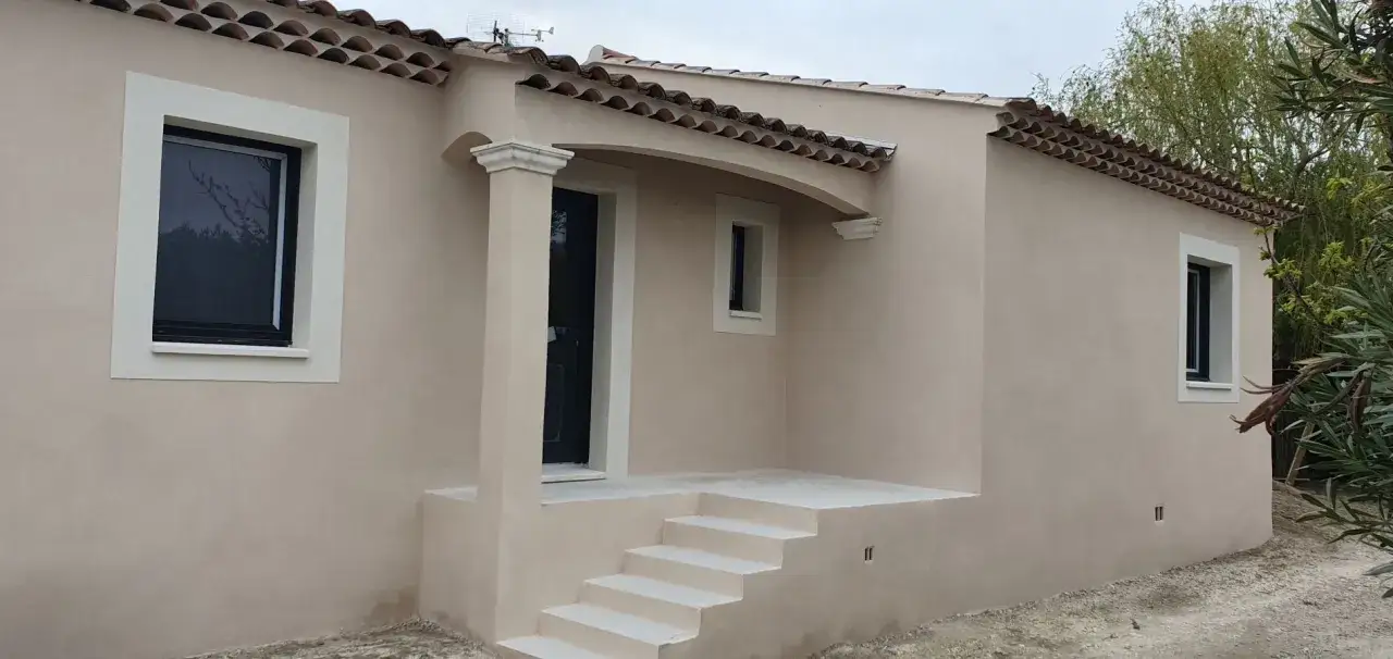 Maison avec reprise enduit gratté, tuiles romanes, porte noire et escalier en pierre.