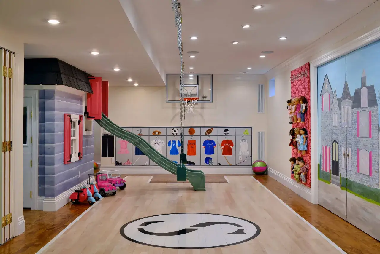 Un sol de salle de jeux avec un toboggan, un panier de basket, des jouets et des décorations murales sportives et de château.
