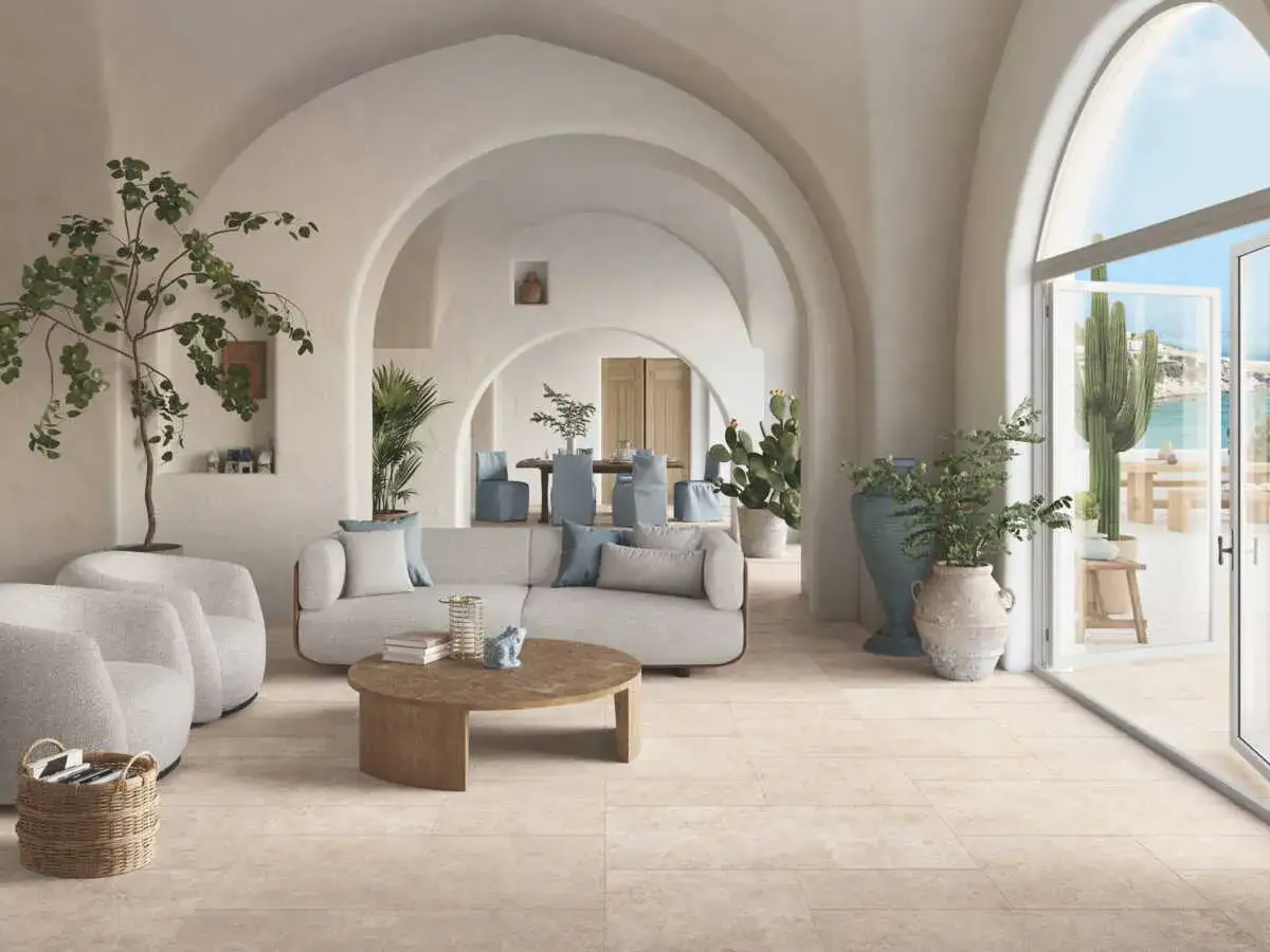 Salon lumineux avec arches, canapés confortables et plantes. Le sol en carrelage clair est idéal pour savoir quel revêtement de sol choisir.