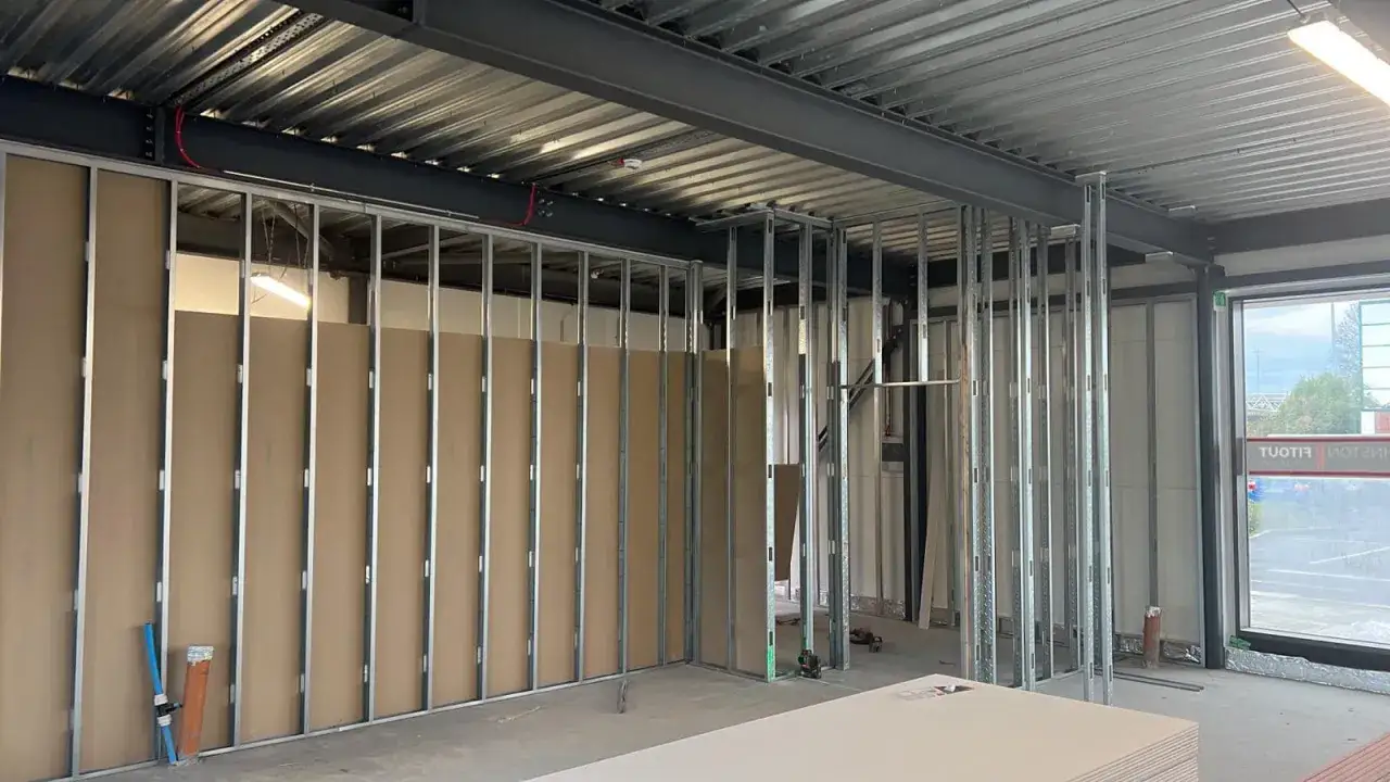 Structure métallique en cours d'installation pour poser du placo. Des plaques de plâtre sont visibles au premier plan.