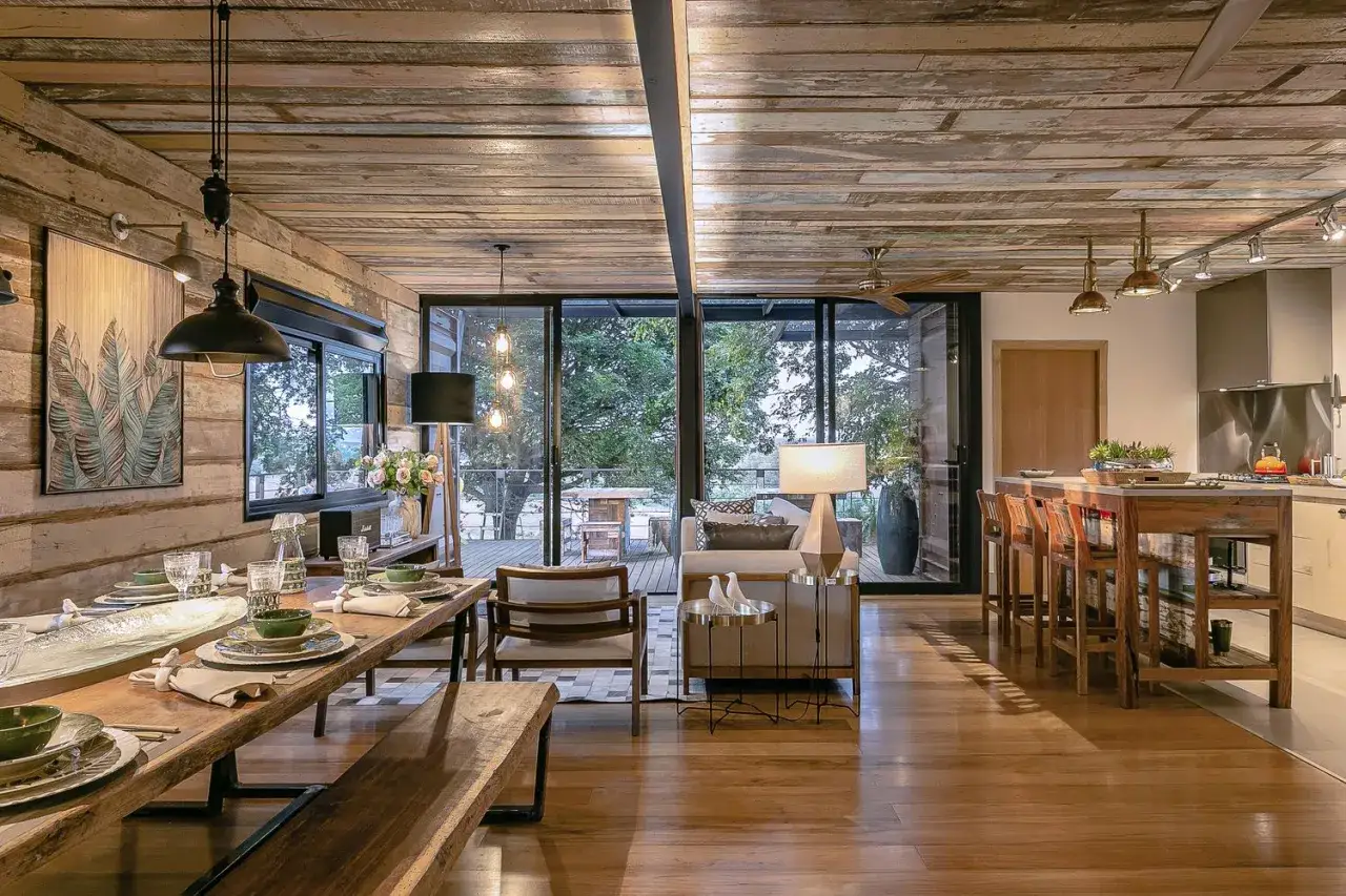 L'intérieur d'une maison container aménagée avec une salle à manger rustique, un salon cosy et une cuisine moderne. Le bois brut domine, créant une ambiance chaleureuse.