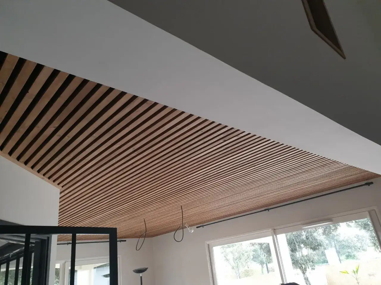 Plafond en lattes de bois, rappelant l'OSB, créant un effet chaleureux et moderne.
