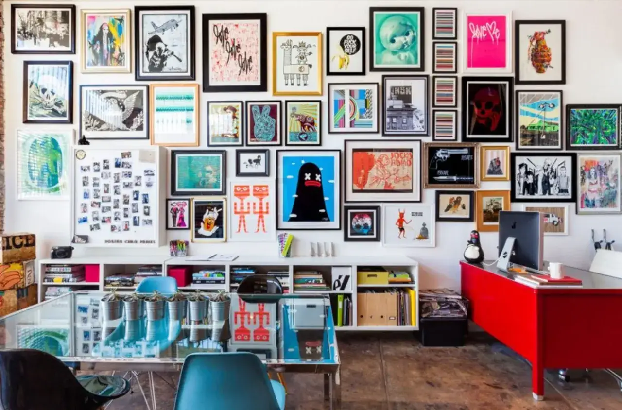 Un mur de cadre rempli d'&oelig;uvres d'art color&eacute;es et vari&eacute;es, allant de la pop art aux illustrations graphiques, cr&eacute;ant une ambiance vibrante et artistique.