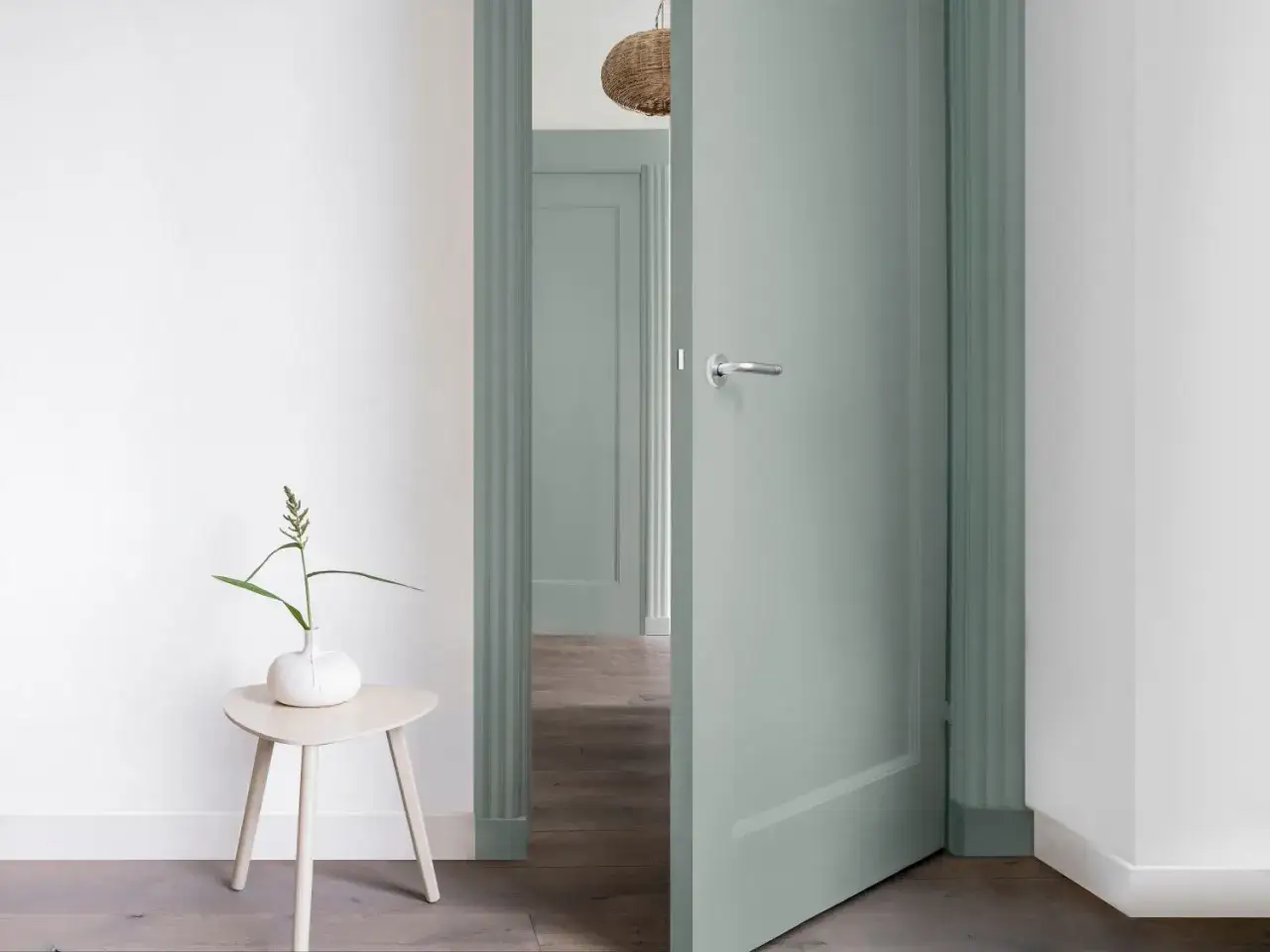 Une porte verte pastel ouverte, encadrée par une moulure assortie. Une idée pour comment habiller une porte avec simplicité et élégance.