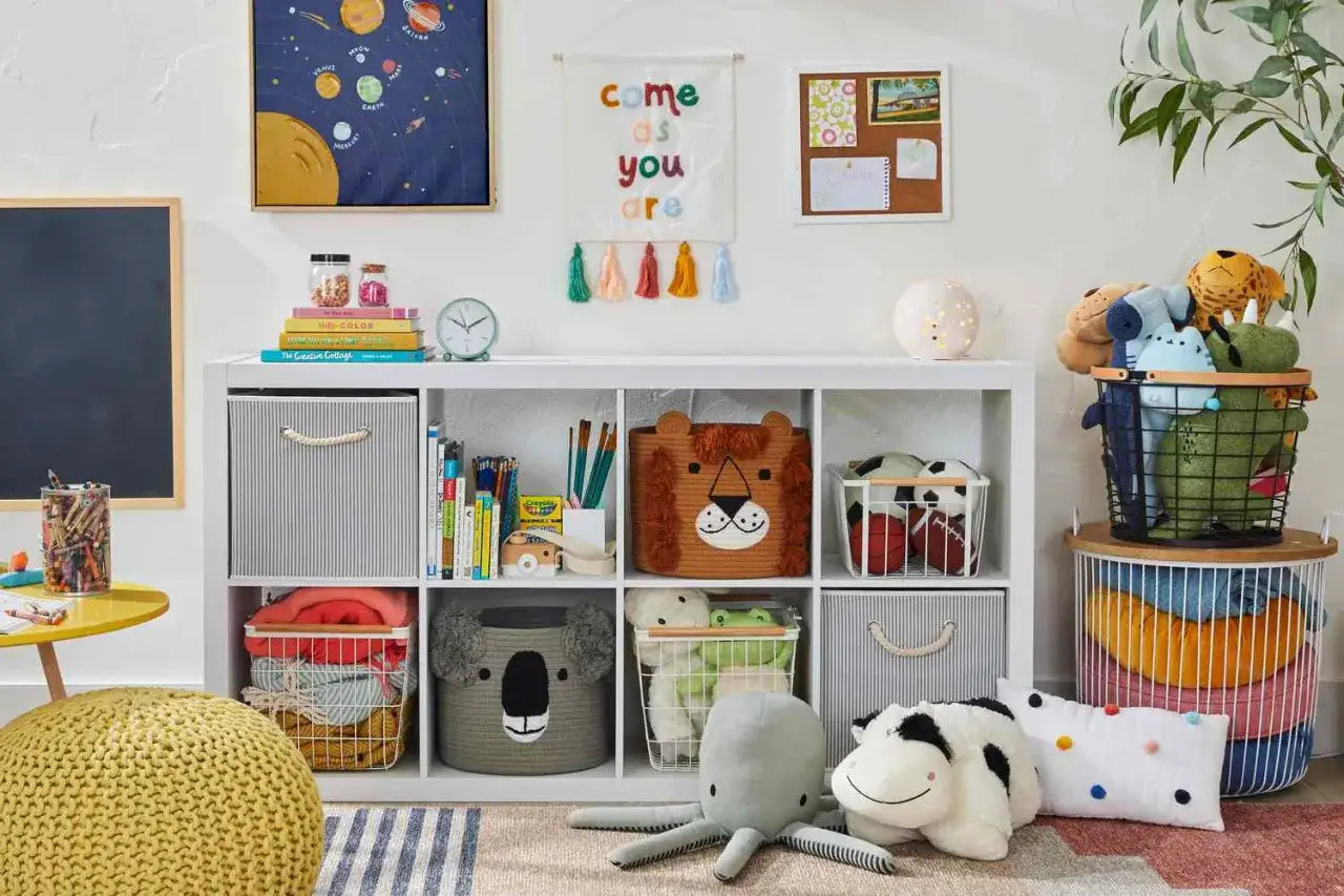 Idées pour aménager petite chambre enfant : étagère modulable, paniers de rangement animaux, peluches et coussins colorés.