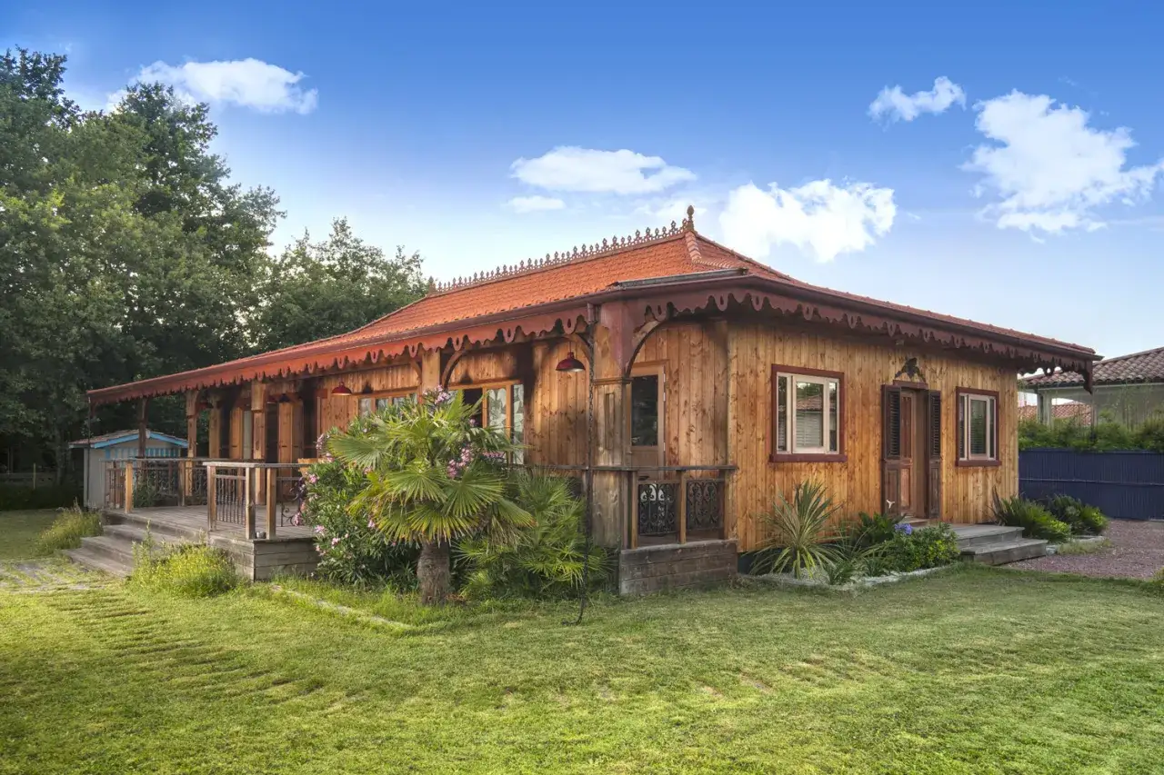 Charmante maison antillaise traditionnelle en bois, avec une véranda, sous un ciel bleu.