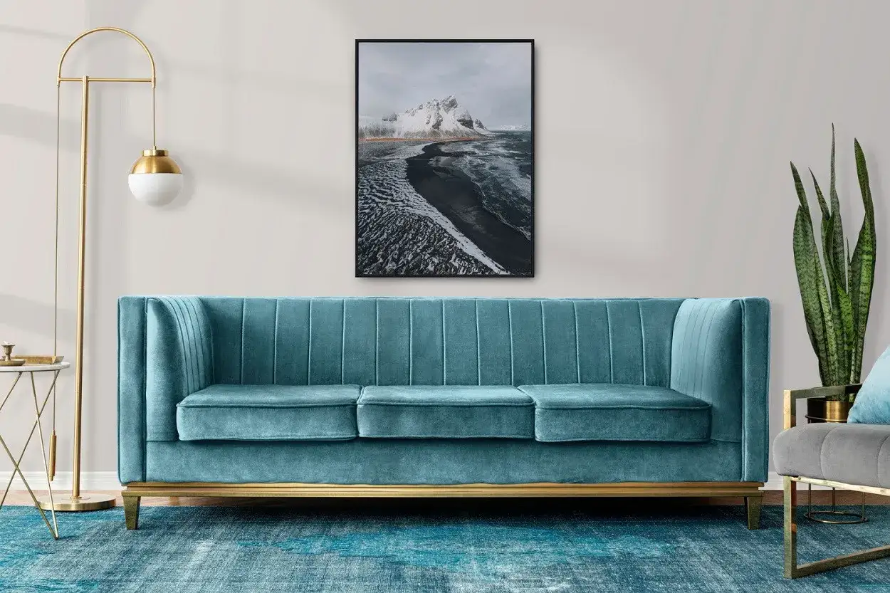 Canapé bleu canard, tapis assorti, tableau de paysage hivernal. Quelle couleur avec le bleu canard ? Le doré du lampadaire et du cadre du canapé s'harmonisent parfaitement.