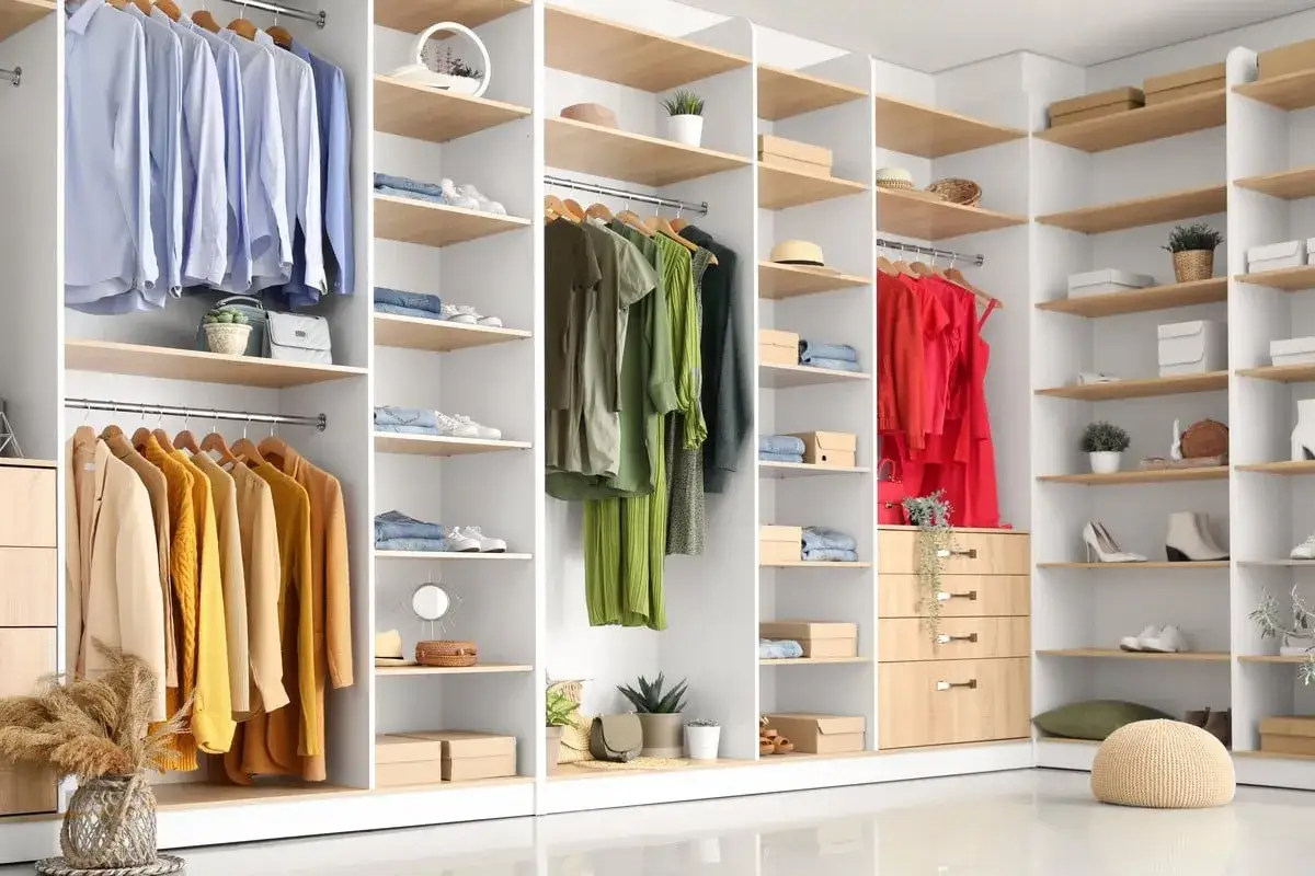 Un dressing bien rangé avec des vêtements suspendus et pliés, des chaussures et des accessoires organisés sur des étagères.