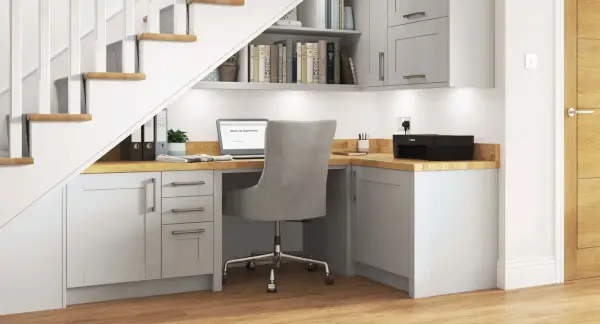 Bureau sous escalier fonctionnel avec ordinateur portable, imprimante et rangements.