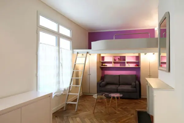 Un studio optimisé de plan 20m2 avec lit mezzanine, canapé, étagères violettes et échelle.