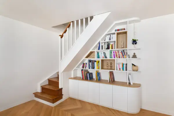 Bibliothèque intégrée dans la cage d'escalier, offrant un espace de rangement astucieux et décoratif.