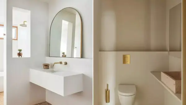 Idées pour décorer ses toilettes : un lavabo suspendu blanc, un miroir arche doré, une chasse d'eau dorée et une brosse WC assortie.