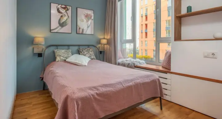 Une chambre d'amis confortable avec un lit douillet, des tableaux de fleurs et une vue sur la ville.