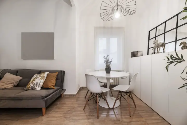 Idée pour aménager salon salle à manger 20m2 : canapé gris, table ronde blanche avec chaises, et rangements muraux.