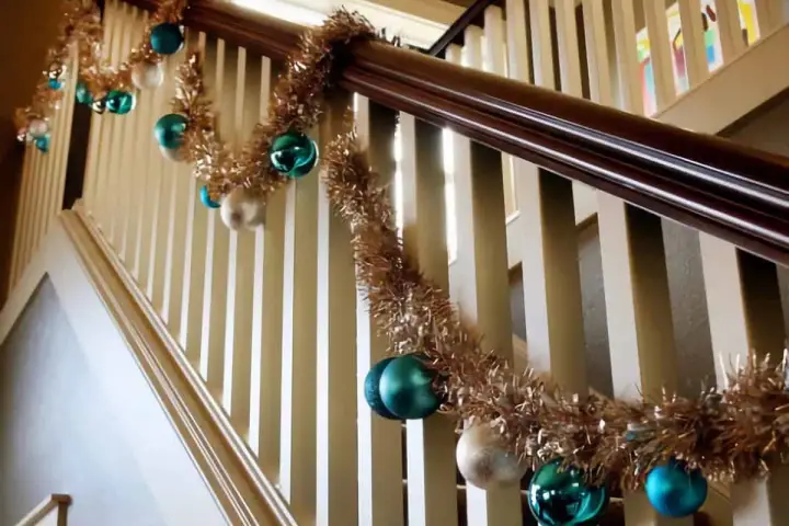 Guirlande dorée et boules de Noël bleues et blanches pour décorer une rampe d'escalier pour Noël.